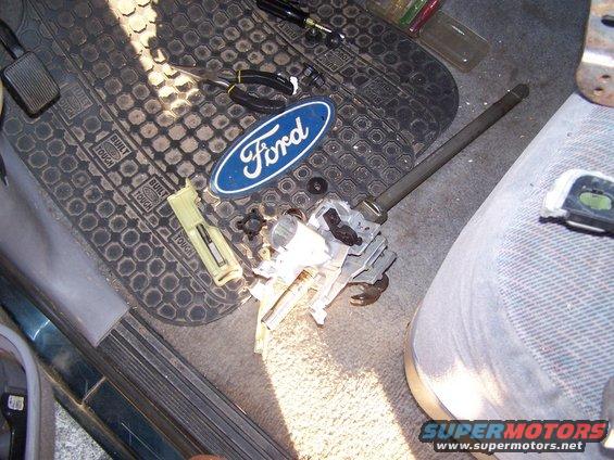 Ford oval emblem and steering column parts on floor mat inside vehicle