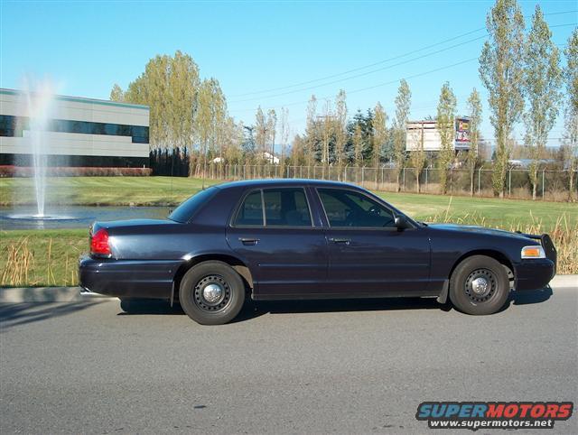 Dark blue sedan parked on asphalt, side view. Black push bumper on front