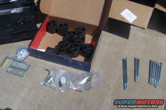 Box of black body lift pucks and hardware on concrete