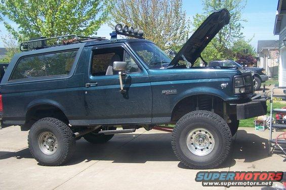 Dark teal 1995 Ford Bronco with lifted suspension, roof rack, and off-road lights