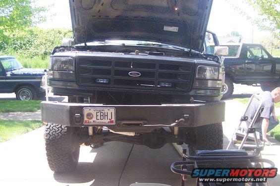 1995 Ford Bronco front view, hood open. Another Ford truck is parked behind it