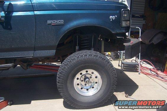 Side view of a dark teal Ford Bronco, showing lifted suspension and large tire. Bronco XLT badge visible
