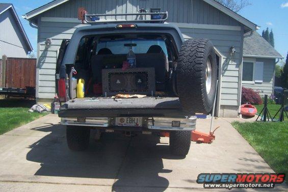 Rear view of lifted SUV with side-mounted spare tire and custom audio system in bed