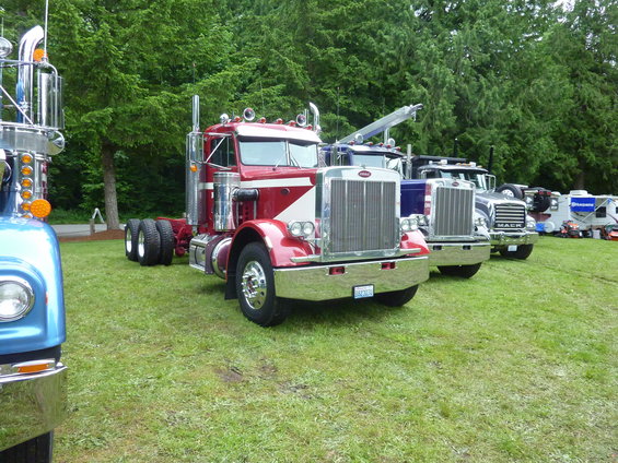 Red and white semi-truck with chrome grille and stacks, parked on grass
