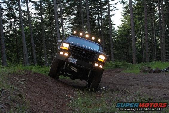 1995 Ford Bronco driving on a dirt trail in a forest, front view