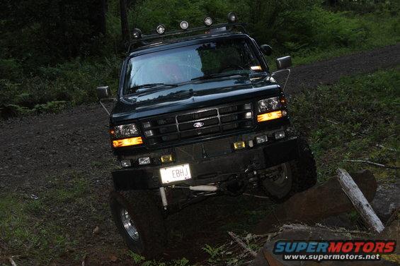 Dark green Ford Bronco on dirt road with trees. License plate reads EBHJ