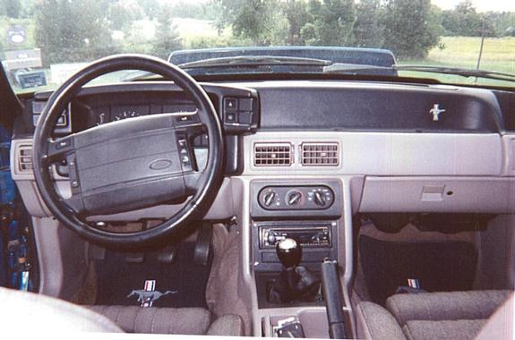 Interior of a 1990 Ford Mustang showing the dashboard, steering wheel, and gear shift