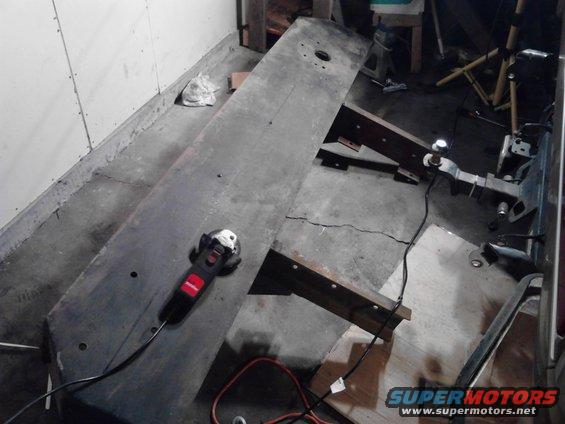 Metal plate with grinder on concrete floor, supported by wooden beams