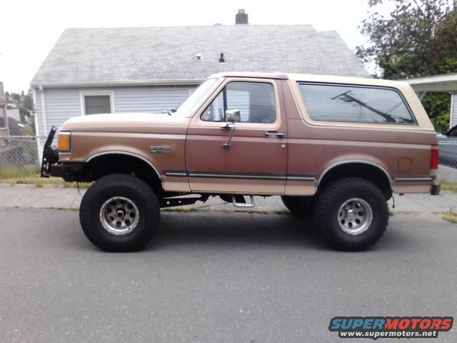 1989 Ford Bronco lifted with aftermarket front bumper and tan top, side view