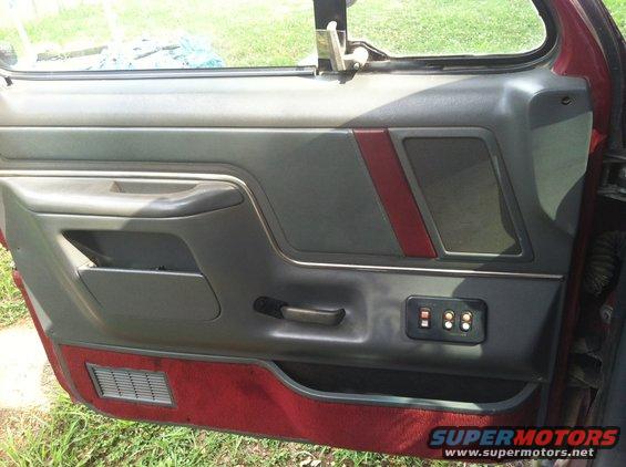Red and gray car door panel with power window controls and a speaker grille