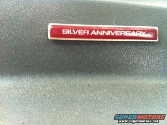 Close-up of a red 'Silver Anniversary' badge on a textured gray surface