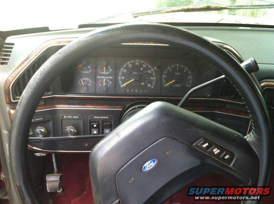 Dashboard view of a Ford truck with a steering wheel, gauges, and controls. The Ford logo is visible on the steering wheel