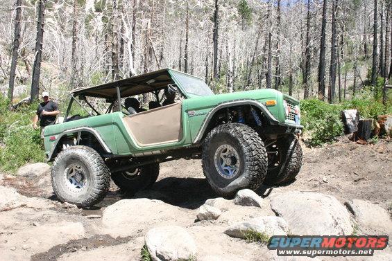 Green Ford Bronco with large tires on rocky terrain