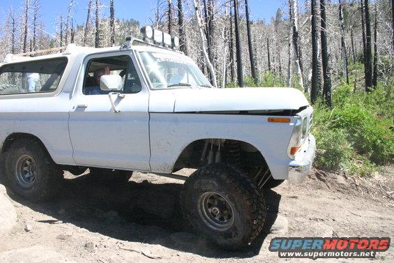 White Ford Bronco with off-road modifications on a rocky trail