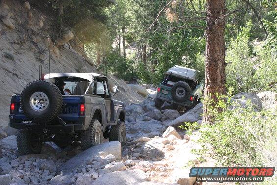 1991 Ford Bronco and a green Jeep navigating a rocky trail