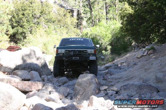 1991 Ford Bronco navigating a rocky trail, windshield banner reads 'ABUSED'
