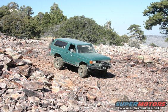 Green SUV with lifted suspension and off-road tires on rocky terrain