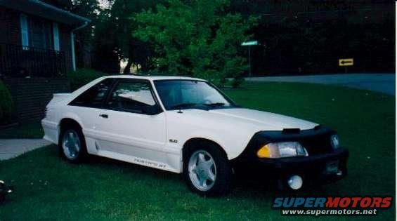 White 1987 Ford Mustang GT coupe with a black bra parked on grass