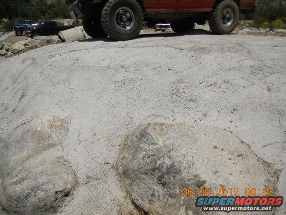 Red off-road vehicle and blue pickup truck on rocky ground