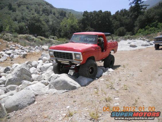 Red lifted 1979 Ford Bronco navigating rocky terrain