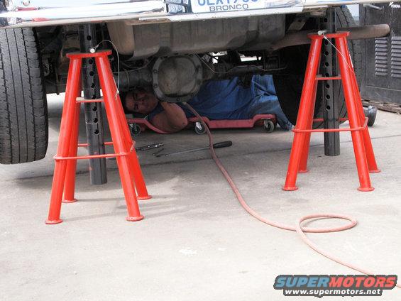 Underneath a 1994 Ford Bronco on jack stands with a mechanic working