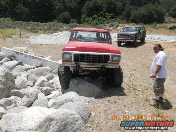 Red Ford Bronco with lifted suspension navigating large rocks