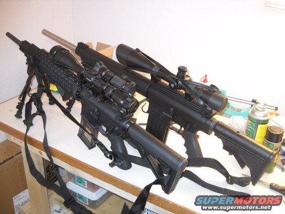 Two black rifles with scopes and bipods on a table. One rifle is in the foreground