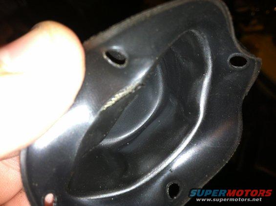 Close-up of a black plastic automotive part with mounting holes