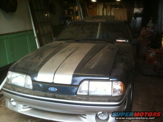 Dusty 1990 Ford Mustang with silver racing stripes on hood and front bumper