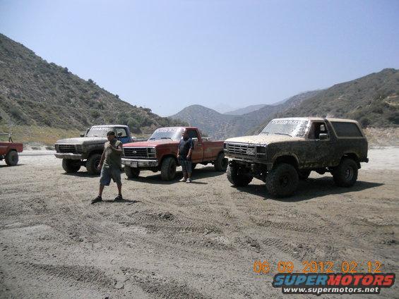Tan Ford Bronco with aftermarket wheels and tires, parked on dirt