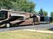 2003 Ford F-350 - A large RV is parked next to a black enclosed trailer on a sunny day.