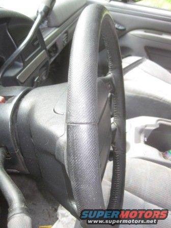 Steering wheel and dashboard of a 1992 Ford Bronco, showing worn seats and a watermarked logo