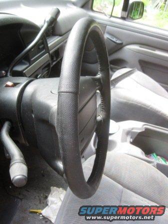 Interior view of a vehicle's steering wheel and dashboard. Watermark reads SUPERMOTORS