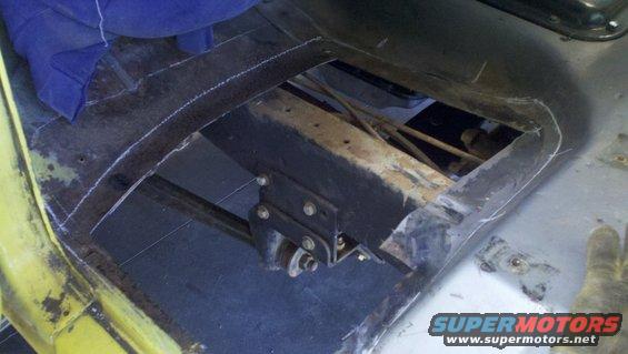 Yellow 1978 Ford Bronco interior floor pan with cutouts and exposed metal frame