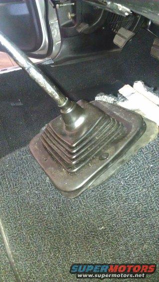 Car interior showing a black rubber gear shifter boot and chrome shifter lever on dark carpet