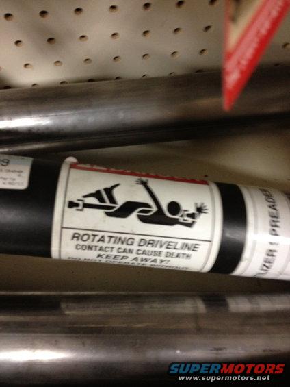 exhaust pipe with a warning label about a rotating driveline