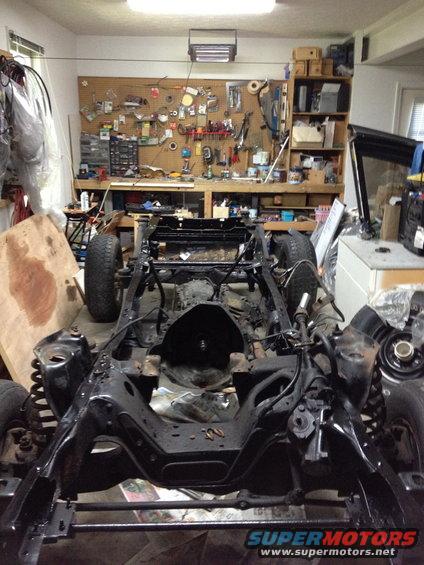 Vehicle frame and chassis in a workshop, front view. Some parts are disassembled