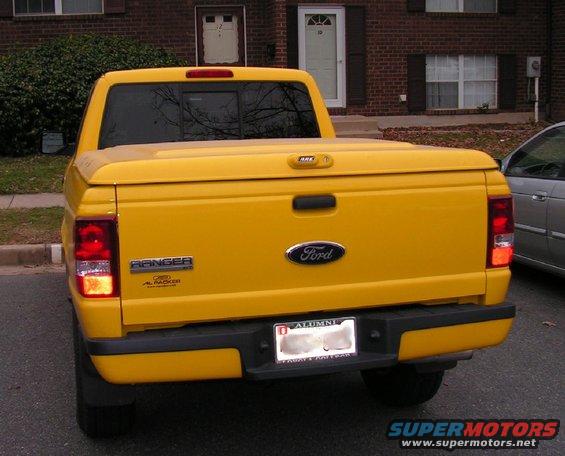 Yellow 1999 Ford Ranger pickup truck rear view, with a tonneau cover and aftermarket bumper