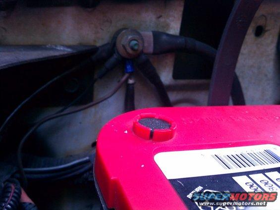 Close-up of car battery terminals and wiring, with a red battery top visible