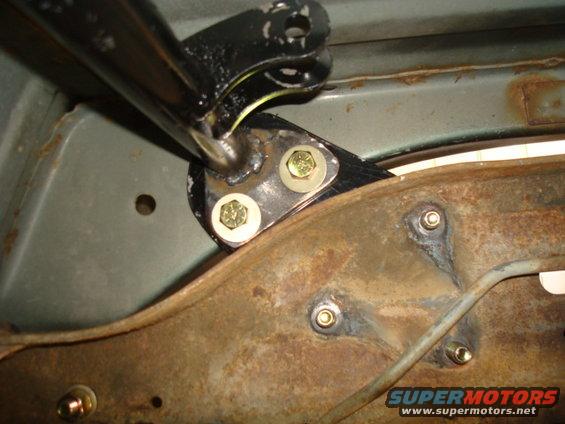 Aftermarket rear shock hoop mount bolted to rusty frame rail