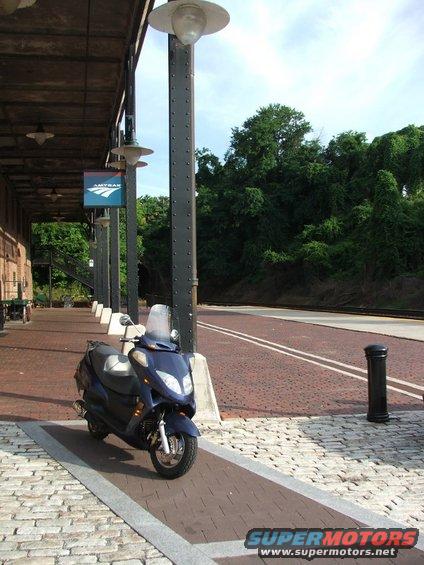 Blue scooter parked at train station platform with Amtrak sign