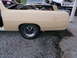 1971 Ford Ranchero - A tan 1970 Ford Ranchero is shown from the side, with its bed filled with parts and other vehicles in the background.