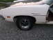 1971 Ford Ranchero - A white Ford Ranchero with a black hood stripe is seen from the side, revealing its interior and rusted lower body panels.