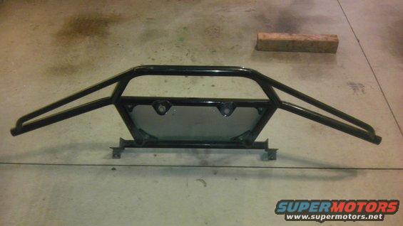 Black metal roll cage with two horizontal bars extending outwards, mounted on a concrete floor
