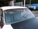 1971 Ford Ranchero - Interior view of a white vehicle with blue seats and a black steering wheel, with another vehicle covered in a blue tarp in the background.