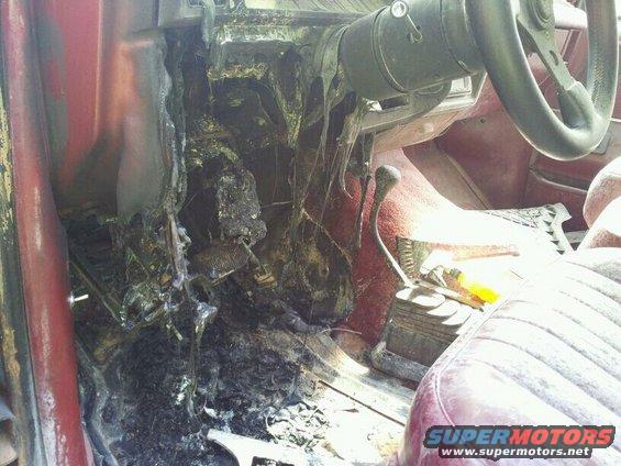 interior of a vehicle showing extensive fire damage to the dashboard and floor area