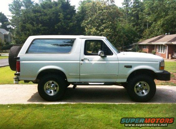 White 1993 Ford Bronco parked on a driveway, side view, with a spare tire mounted on the rear
