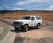 1993 Ford Bronco - A white 1993 Ford Bronco is parked on a dirt road with a construction site in the background.