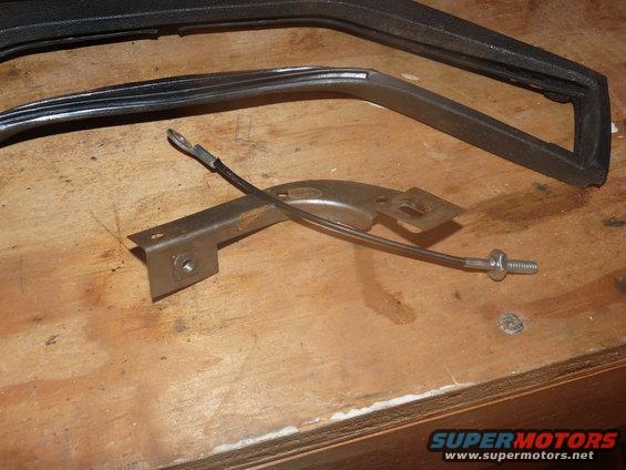 Car door trim piece and a metal bracket with a cable attached