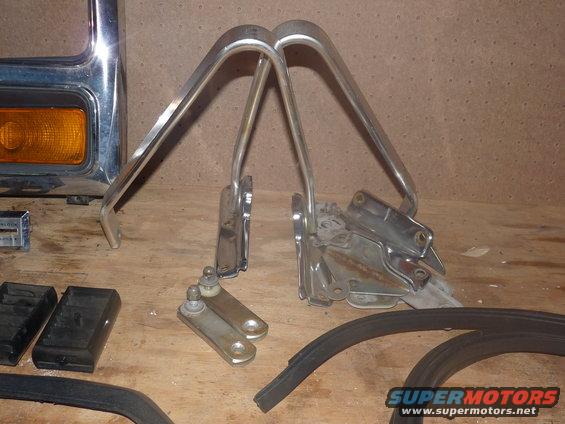 Chrome hood hinges and fender trim pieces on a wooden surface